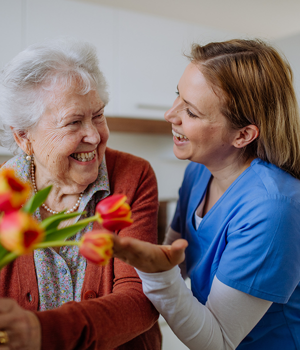 Senior woman and nurse with tulip bouquet. Physical therapy at Addison Pointe