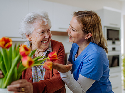 Senior woman and nurse with tulip bouquet. Physical therapy at Addison Pointe
