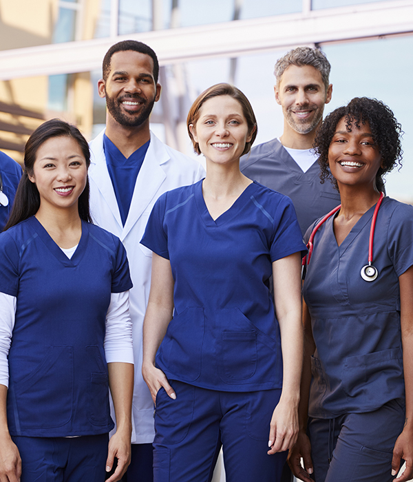 Smiling medical team standing together outside a hospital Hands holding